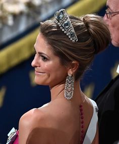 a woman wearing a tiara standing next to an older man