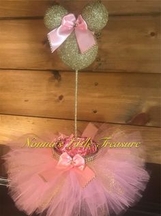 a pink and gold minnie mouse tutule hanging from a wall with a bow on it