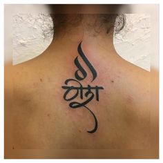 the back of a woman's neck with an om shant tattoo on it