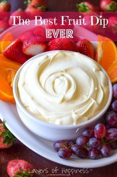 a white plate topped with oranges and strawberries next to a bowl of cream cheese