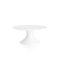 a white cake plate sitting on top of a white tableclothed floor with an oval shaped base