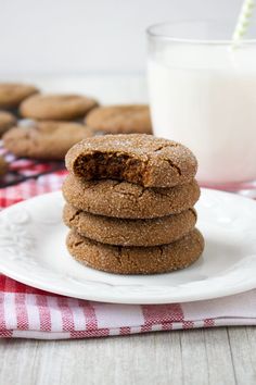 a stack of cookies sitting on top of a white plate next to a glass of milk