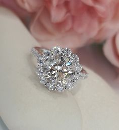 a close up of a diamond ring with flowers in the background