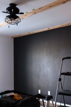 a room that has been painted black and is being worked on with a ladder in the foreground