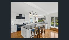 a large kitchen with an island and bar stools next to the stove top oven