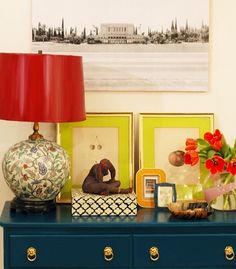 a blue dresser with pictures on it and a red lamp