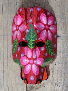 a red mask with pink flowers painted on it