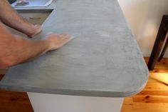 a man is sanding up the top of a table with his feet on it