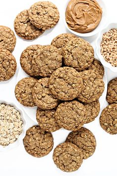 oatmeal cookies and peanut butter in bowls on a white surface with spoons