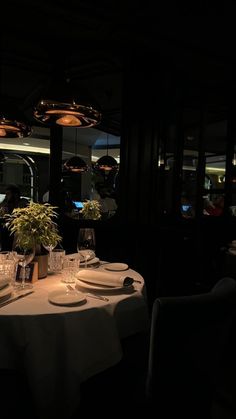 a dimly lit dining room with white table cloths and place settings on the tables