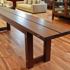 a large wooden table sitting on top of a hard wood floor next to a couch