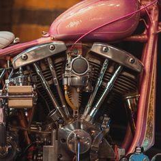 a pink motorcycle parked in a garage next to a wooden wall and flooring with other items on top of it