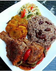 a white plate topped with meat, rice and veggies on top of a table