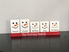 four small blocks with the names of three different families in front of a snowman