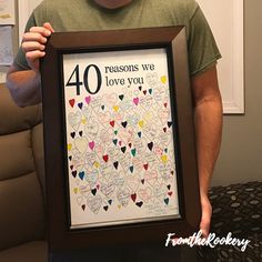 a man holding up a framed poster with the words, 40 reasons we love you