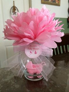 a pink flower in a clear vase on top of a table with a baby carriage tag