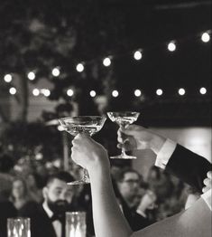 black and white photograph of two people toasting with wine glasses in front of an audience