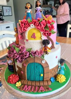 a birthday cake decorated with princess figures and flowers