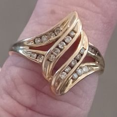 a woman's hand holding a gold ring with white stones on it and two rows of diamonds in the middle