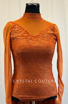 Rust orange leotard has mock neck and long sleeves with finger loops. Long lycra back skirt is attached. Bodice of leotard is lace with Gold shimmer. Decolletage, sleeves, and back are mesh. More lace banding details on back with full zip closure. **Costume in image is an AL, Photographed on an AM/AL Mannequin with Measurements of: Bust 39", Ribcage 34", Waist 33", Hip 40", Girth 60" Fitted Long Sleeve Leotard For Dance, Elegant Long Sleeve Party Unitard, Fitted Leotard With Thumbholes, Elegant Stretch Leotard For Party, Elegant Fitted Unitard For Party, Fitted Long Sleeve Fall Leotard, Fitted Party Unitard With Thumbholes, Fitted High Neck Unitard For Fall, Long Sleeve Dance Unitard