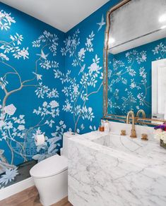 a bathroom decorated in blue and white with flowers painted on the wall next to the toilet