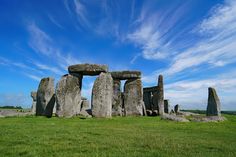 the stonehenge monument in england is surrounded by green grass and blue skies with wispy clouds