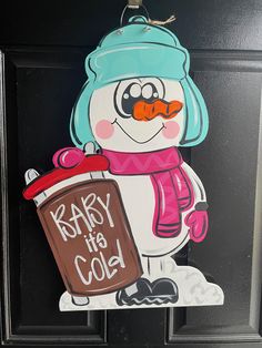 a door hanger with a snowman holding a sign that says baby it's cold