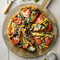 a pizza with tomatoes, cheese and other toppings on a cutting board next to a can of ketchup