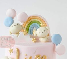 a pink cake topped with two bears and balloons