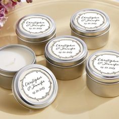 four small tins with labels on them sitting on a table next to flowers and a vase