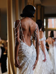 the back of a woman's wedding dress as she stands in front of other women