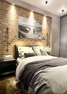 a bedroom with brick walls and lights above the bed, along with a painting on the wall