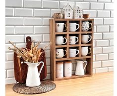 a wooden shelf filled with coffee mugs next to a white vase on top of a table