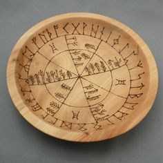 a wooden bowl with writing on it and arrows in the middle, sitting on a table