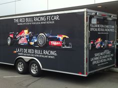 an enclosed trailer with a red bull racing car on it's side