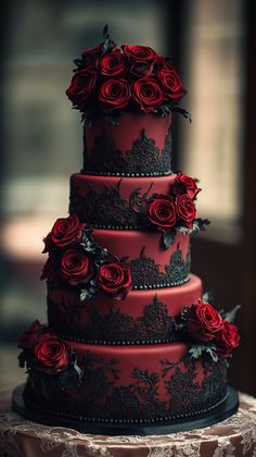 a red and black wedding cake with roses on it's tiers is sitting on a table