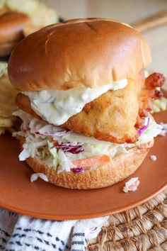 a chicken sandwich with coleslaw and mayonnaise on an orange plate