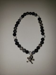 A stretchy beaded bracelet with a skull abd crossbones charm. Casual Skull Jewelry For Gifts, Adjustable Emo Style Bracelets, Casual Skull-shaped Jewelry Gift, Casual Skull-shaped Gift Jewelry, Handmade Black Gothic Bracelets, Casual Skull-shaped Jewelry For Gifts, Gothic Adjustable Black Beaded Bracelets, Pirate Jewelry Bracelets, Pirate Bracelet