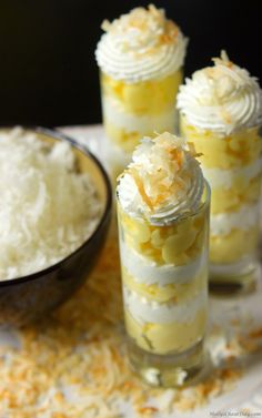 three desserts in small glass containers with whipped cream and pineapple topping on top