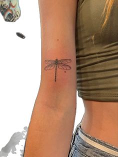 a woman's arm with a small dragonfly tattoo on it