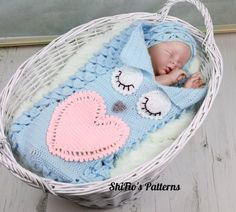 a baby is sleeping in a basket with a blanket on it's head and eyes