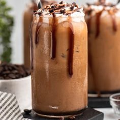 two glasses filled with chocolate milkshakes sitting on top of a white tablecloth