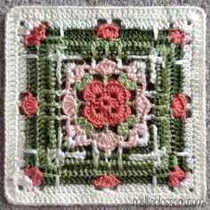 a crocheted square with pink flowers on it and green squares in the middle