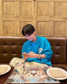 a boy sitting at a table looking at his cell phone