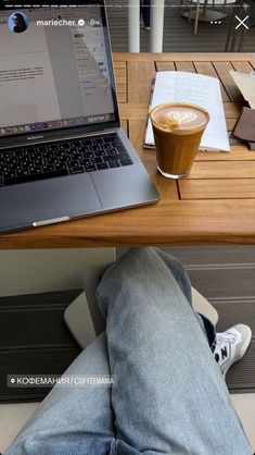 a laptop computer sitting on top of a wooden table next to a cup of coffee