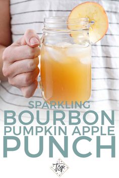 a person holding a mason jar filled with bourbon pumpkin apple punch