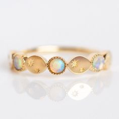 a gold ring with opal stones and stars on the side, sitting on a white surface