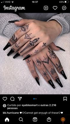 a person with long black nails and tattoos on their hands, holding onto an instagram