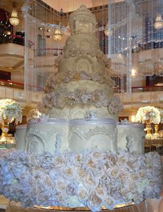 a large white wedding cake sitting on top of a table in front of chandeliers