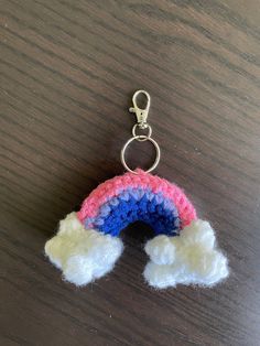 a crocheted rainbow keychain hanging on a wooden table with a metal hook